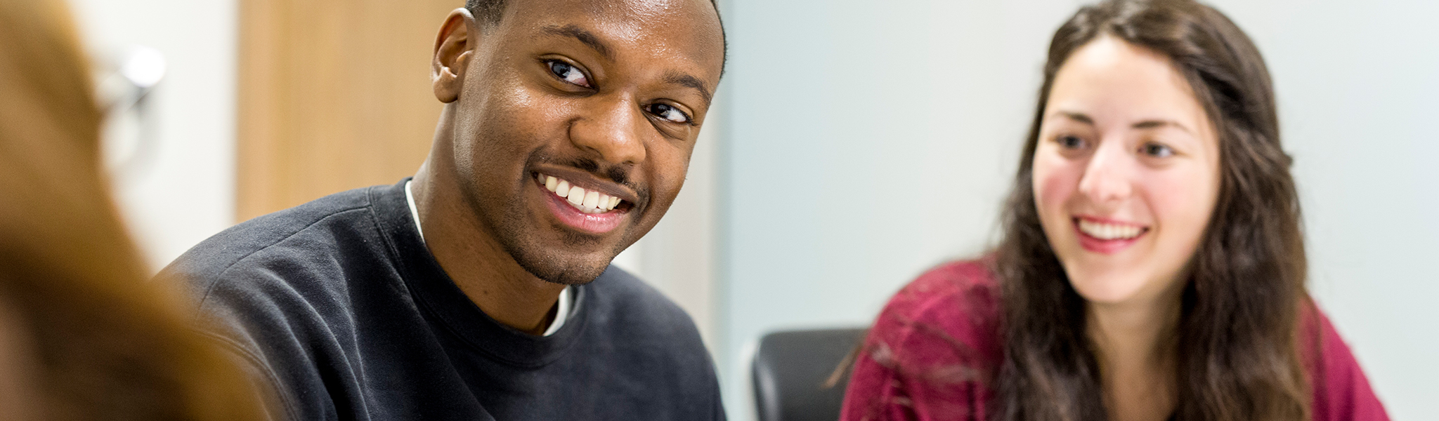 Two students sitting in a meeting room smiling