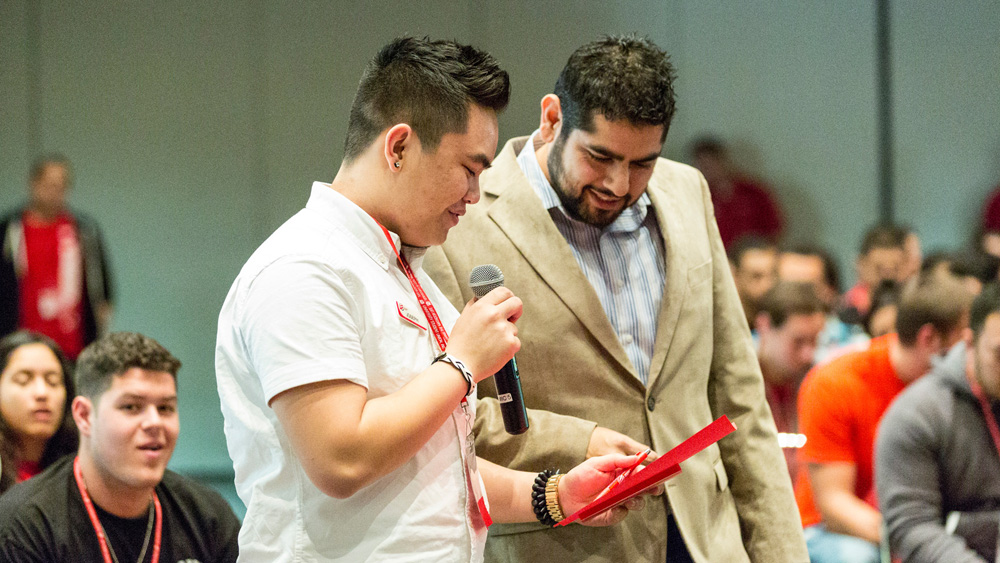 Joseph Cayanan talks with a microphone while Kevin Lizarraga supervises at the winter 2013 Student Summit