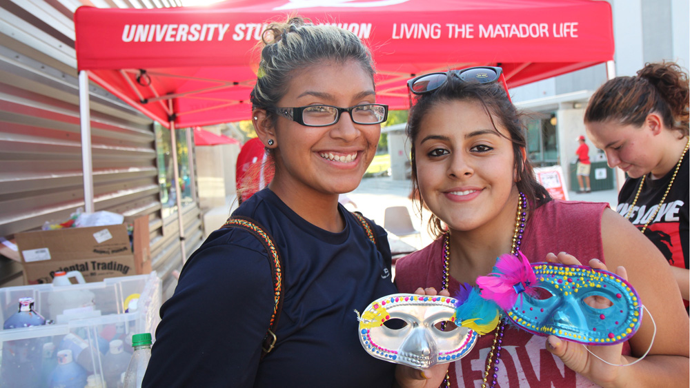 Two students smile and show off their Craft Corner creations at the fall 2012 Matafest event