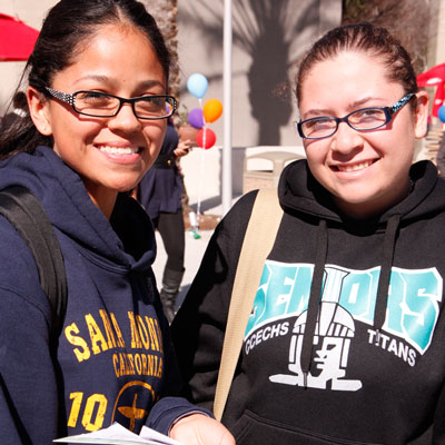 Two female students smiling and standing in the USU Plaza del Sol
