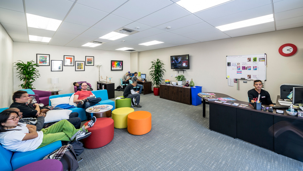 A wide-angle photo of the Pride Center shows students interacting inside