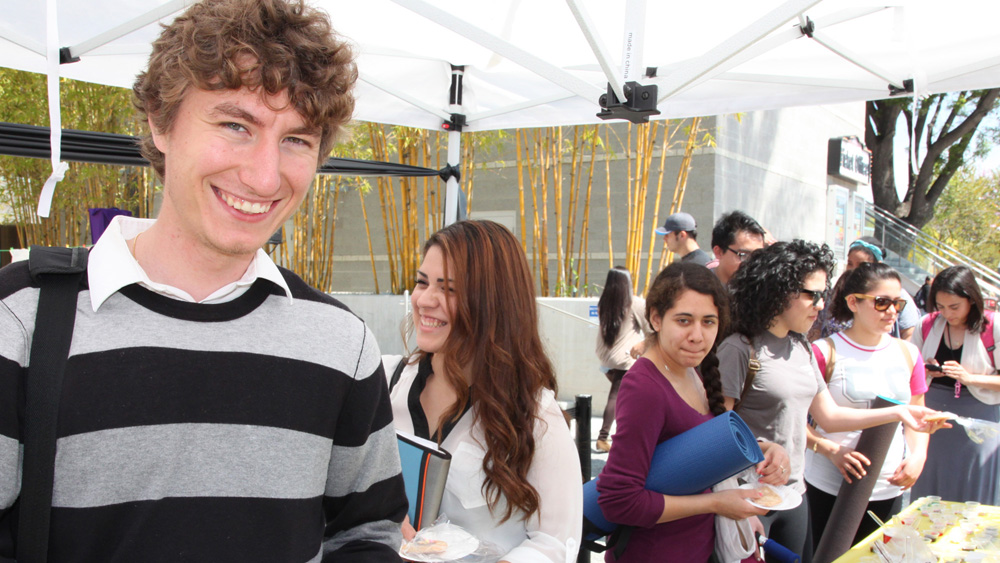 Students smile while waiting in line for food at the Art 180 event