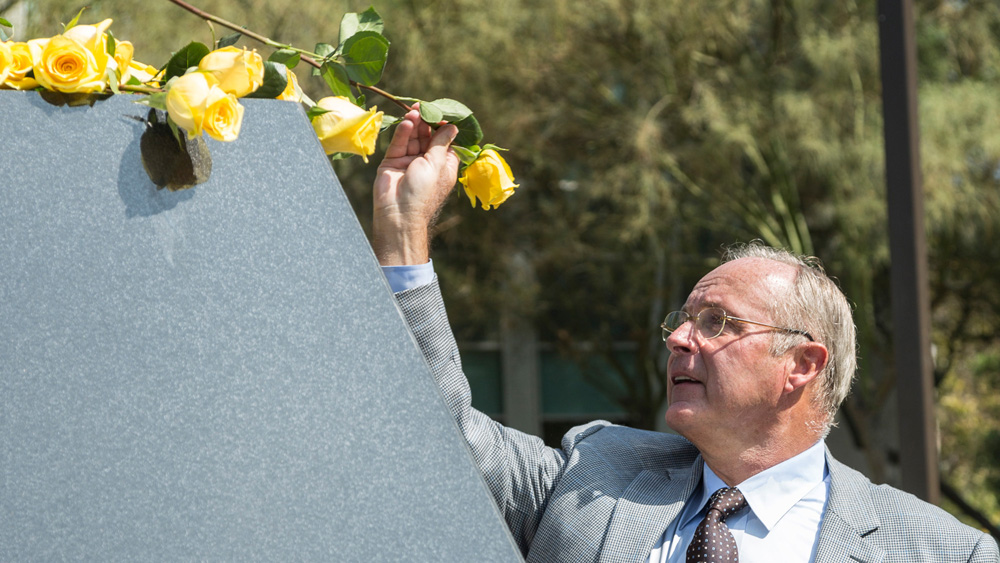 CSUN presidential spouse John Wujack places a yellow rose at the base of the Matador statue during the VRC Grand Opening